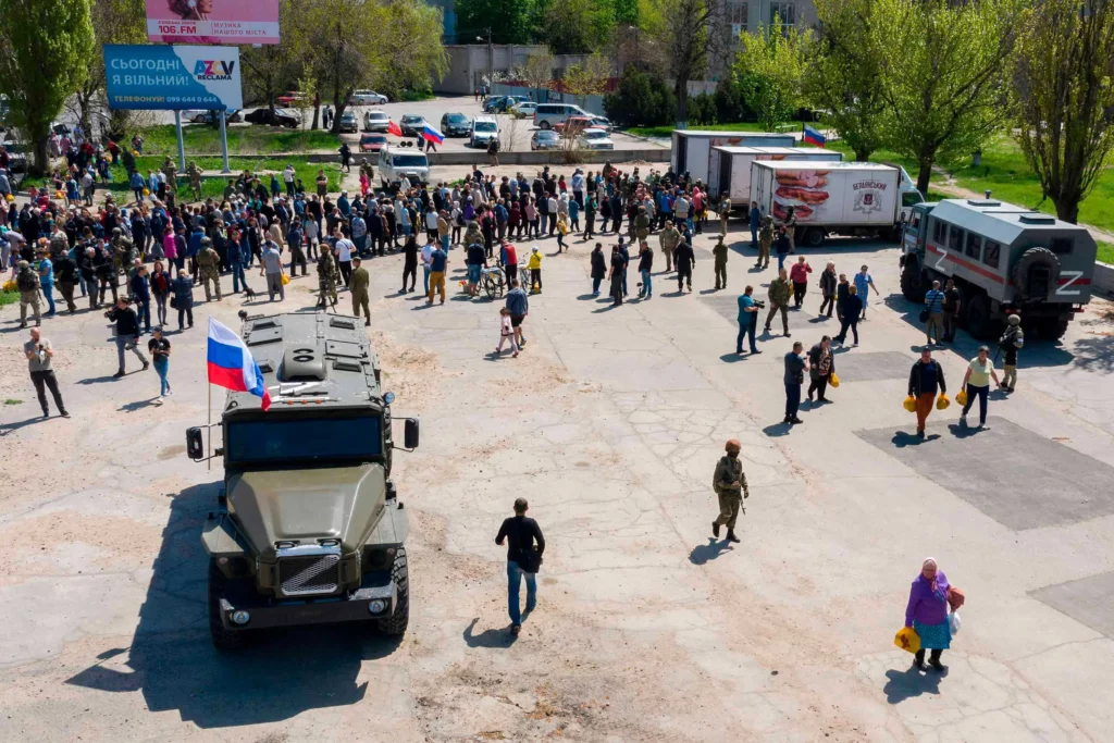 Місцеві жителі та біженці з Донецької області стоять у черзі за гуманітарною допомогою, яку роздають з російських військових вантажівок у Бердянську